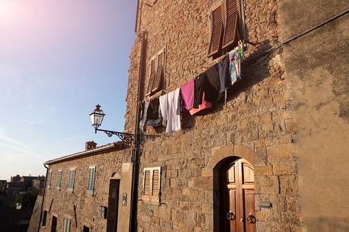 Volterra, Tuscany, Italy. August 2020. On the facade of one of the characteristic houses of the historic center, clothes hanging in the evening sun. Characteristic glimpse of the village.