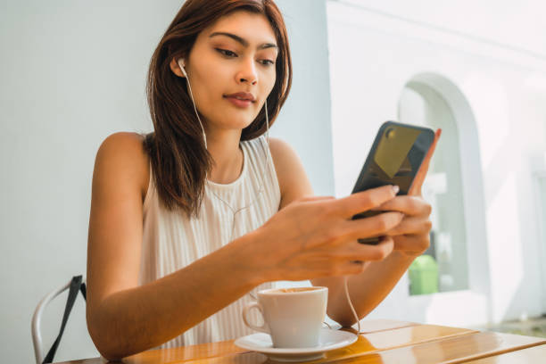 istock Young latin woman using phone at coffee shop. 1325923006