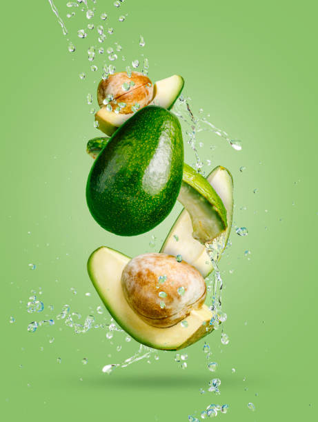 Fresh avocado cut into slices with water drops splash flying in the air and levitate on a mint green background. Healthy diet ingredient recipe. Trendy motion food composition. Creative fruit concept. Fresh avocado cut into slices with water drops splash flying in the air and levitate on a mint green background. Healthy diet ingredient recipe. Trendy motion food composition. Creative fruit concept. levitation photos stock pictures, royalty-free photos & images