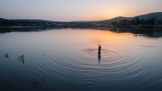 Aerial view photo of a young woman enjoying summer sunset on the lake