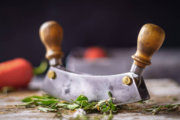 Mezzaluna on cutting board Mezzaluna and sliced herbs on cutting board, soft low shallow focus mezzaluna stock pictures, royalty-free photos & images