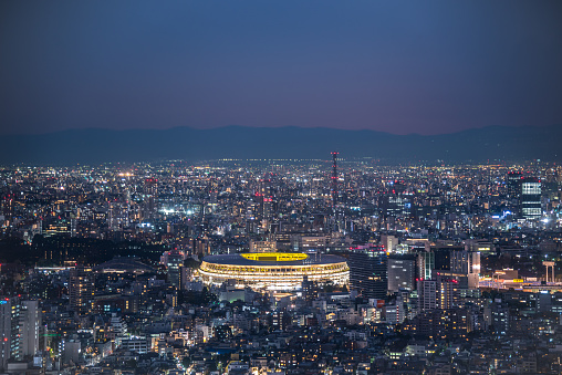 TOKYO, JAPAN - November 30, 2019 : Overhead aerial view of the new National Stadium with Tokyo's skyline in twilight time, fully completed main stadium for Tokyo Olympic Summer Games 2020