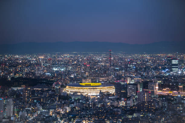 Aerial view of Japan National Stadium in twilight TOKYO, JAPAN - November 30, 2019 : Overhead aerial view of the new National Stadium with Tokyo's skyline in twilight time, fully completed main stadium for Tokyo Olympic Summer Games 2020 olympic city stock pictures, royalty-free photos & images