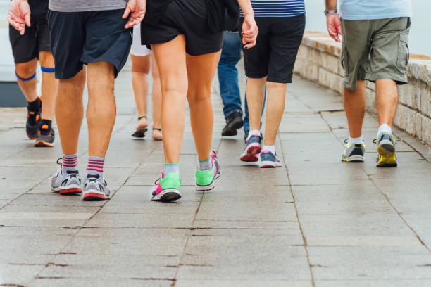 Several people walk down a sidewalk doing exercise stock photo