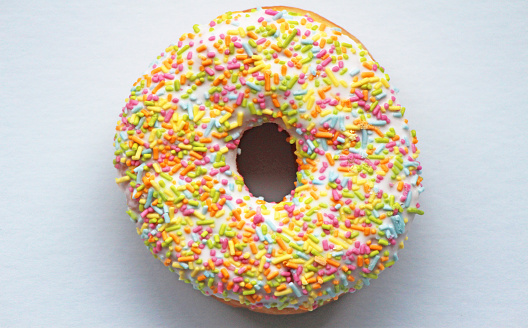 A brightly colored doughnut on a light blue background.