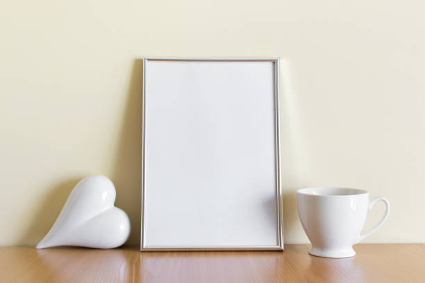 istock Mockup template with A4 silver frame, white porcelein heart and porcelein white cup 1325940688