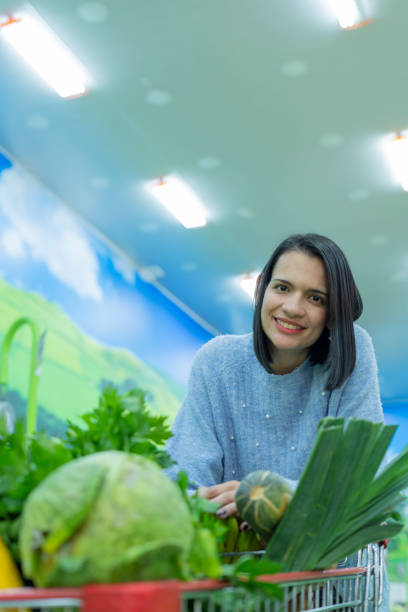 istock Young customer looks at the camera in a portrait while selecting the products that she will buy in the vegetable and fruit store 1325943333