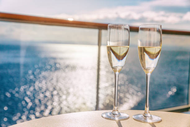 Luxury cruise ship travel champagne glasses on balcony deck with ocean sunset view on Caribbean vacation. Drinks in sun flare on cruise holiday destination. Luxury cruise ship travel champagne glasses on balcony deck with ocean sunset view on Caribbean vacation. Drinks in sun flare on cruise holiday destination. boat deck stock pictures, royalty-free photos & images