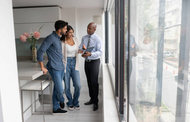 agente de bienes raíces hablando con una pareja que compra un apartamento - inmobiliaria fotografías e imágenes de stock