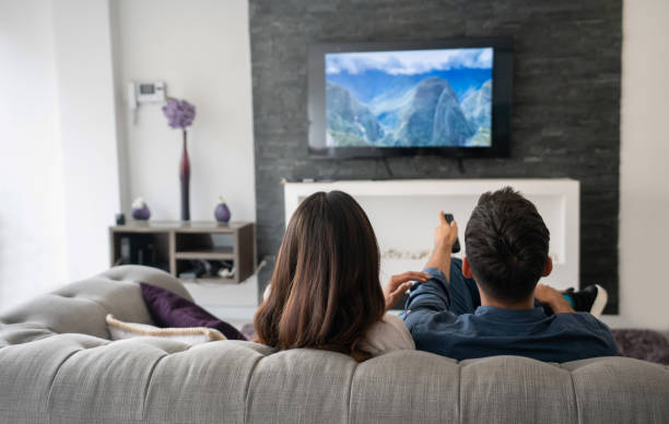coppia a casa a guardare la tv in salotto - guardare la tv foto e immagini stock