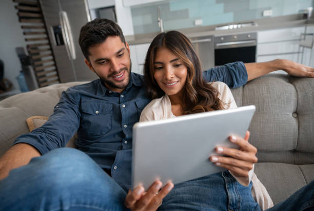 istock Happy couple at home watching videos on a tablet 1325947443