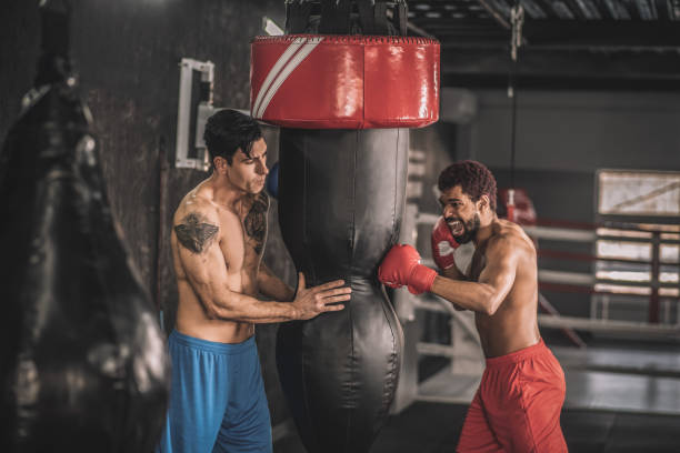 istock Two men exercising in a gym and kicking the sandbag 1325947700