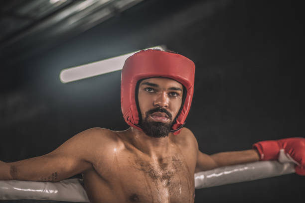 After the fight. Dark-skinned kickboxer in a red hemlet looking tired after the fight