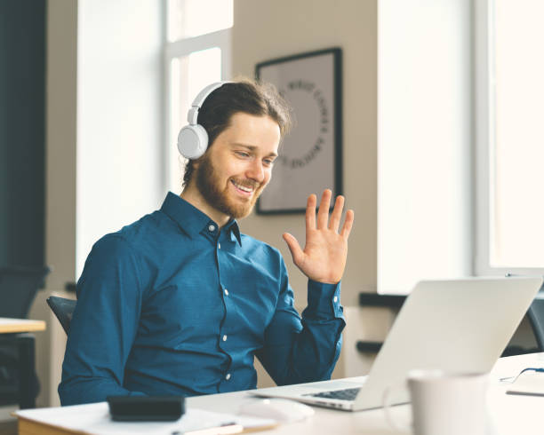 istock Young happy man office worker in headphones smiling during video call 1325947801
