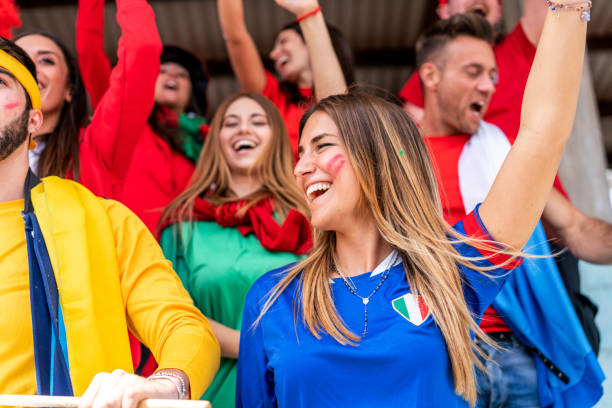 istock Multi colored fans at stadium are supporting their team 1325948658