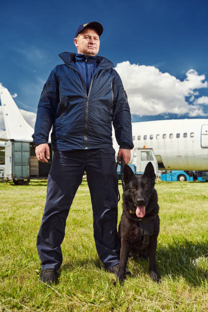 istock Male security officer with dog standing outdoors at aerodrome 1325948723