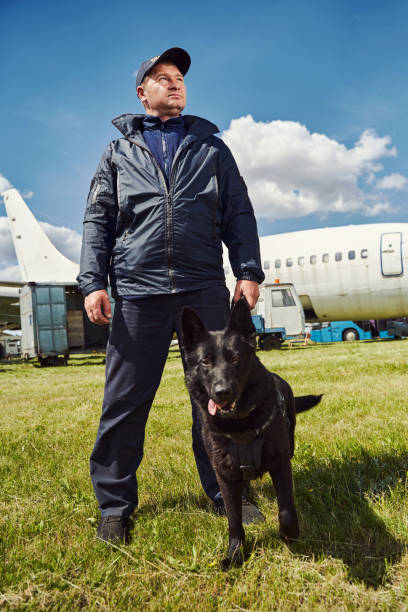 istock Security officer with detection dog standing outdoors at aerodrome 1325948725