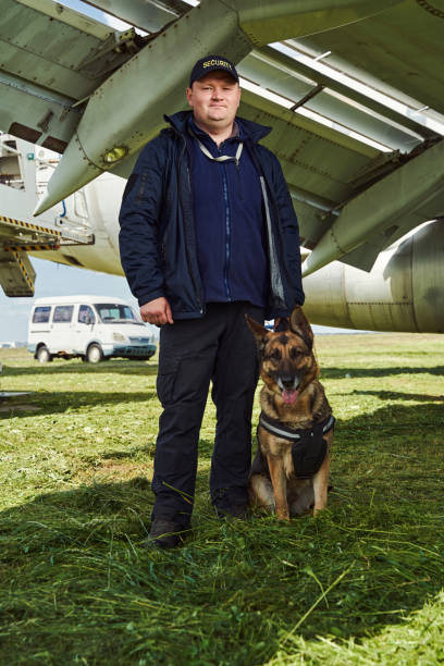 istock Male security worker with dog standing outdoors at airfield 1325948731