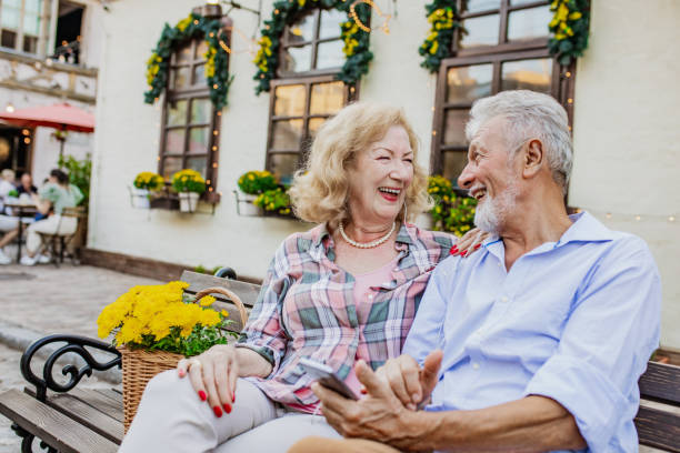istock Happy senior couple sitting on a park bench and using mobile phone 1325952918