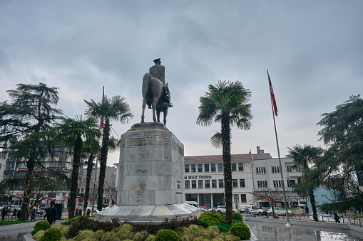 29.03.2021. Bursa Turkey. Sculpture of Ataturk founder of Turkish Republic in center of Bursa (heykel) during rainy and overcast weather with Turkish flag and sculpture covered by trees