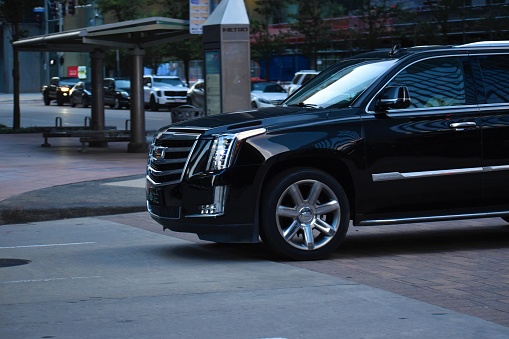 Black Cadillac Escalade cruses in the evening in downtown Houston TX. June 2021