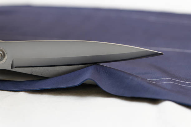 istock The tailor cuts the fabric with scissors on the table. Close up view. 1325957955