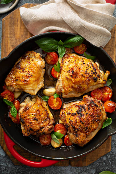 chicken thighs roasted with tomatoes and garlic - chicken thighs imagens e fotografias de stock