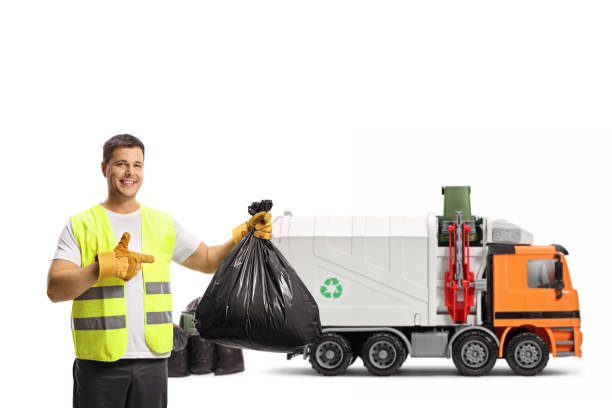 istock Garbage man with a truck holding a plastic bin bag and pointing 1325962118