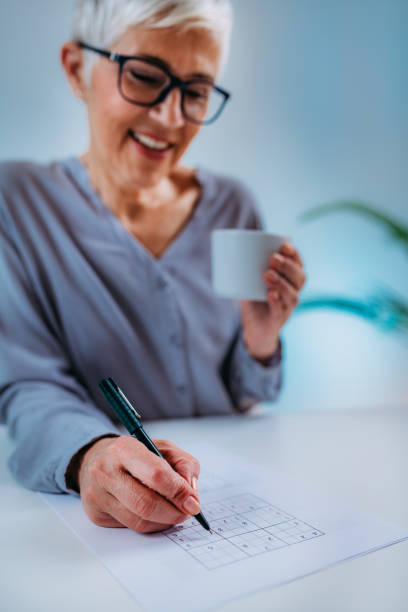 Senior Woman Solving Sudoku Puzzle. Cognitive Therapy for Senior Woman. Senior woman solving sudoku puzzle game. Cognitive enhancement therapy for seniors. neuropsychology stock pictures, royalty-free photos & images