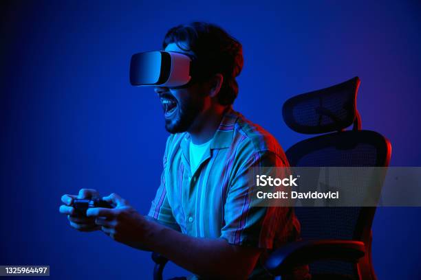 Man Screams And Plays With Joystick In Vr Glasses While Sitting On Chair Stock Photo - Download Image Now