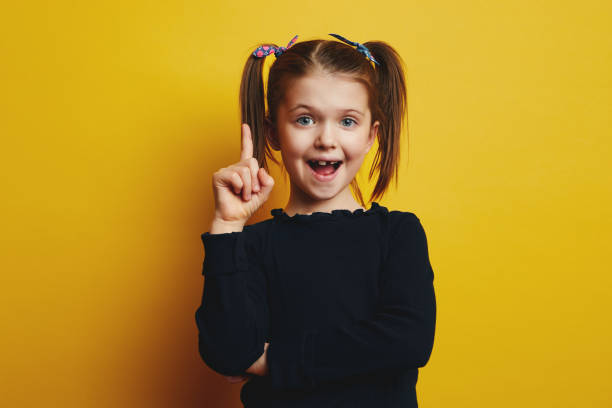 istock Smart cute girl opening mouth and pointing up while having a great idea 1325964501