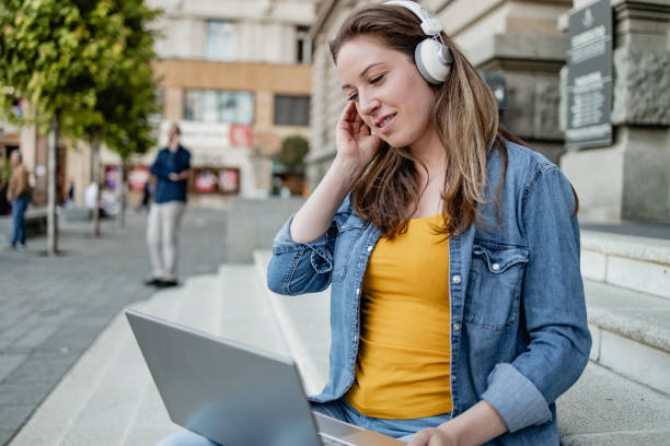 istock Young woman is using laptop in front of the University 1325967701