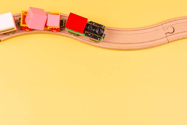 istock Toy train with curved wooden railways on yellow background. Top view 1325970077