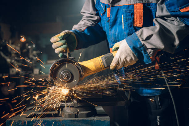 istock Locksmith in special clothes and goggles works in production. Metal processing with angle grinder. Sparks in metalworking 1325971197