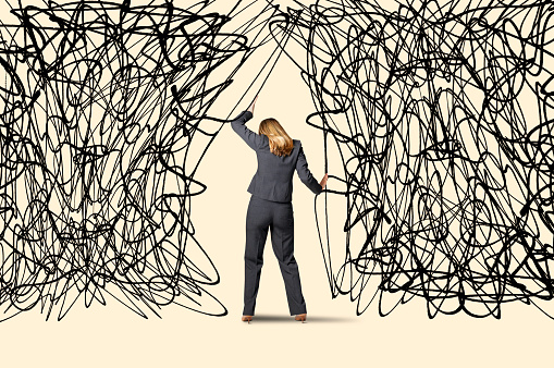 A woman attempts to push a large cloud of randomly scribbled lines out of her way.