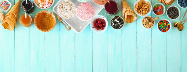 летний стол с мороженым сверху окаймлен на синем деревянном фоне - ice cream sundae стоковые фото и изображения
