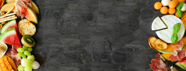 istock Summer fruit theme charcuterie corner border against a dark slate background 1325973056