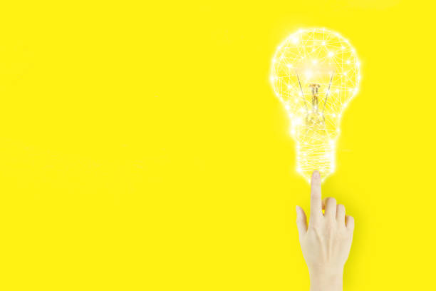 istock Young woman's hand finger pointing with light bulp hologram on yellow background. Creative idea. Concept of idea and innovation. 1325976058