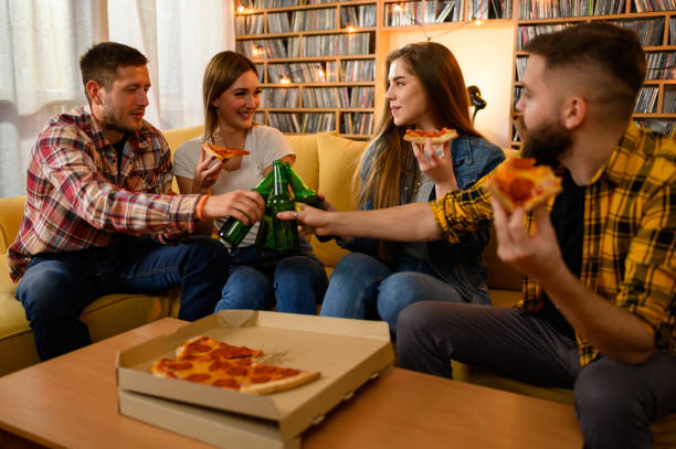 istock Friends eating pizza on a house party and having fun while drinking beer 1325979097