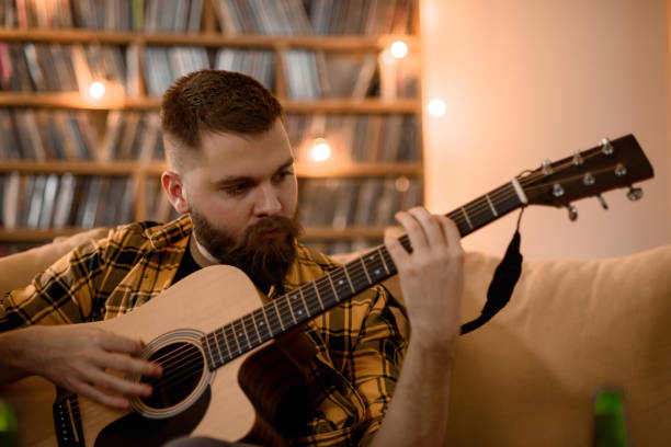istock Young handsome man playing guitar at home 1325979158