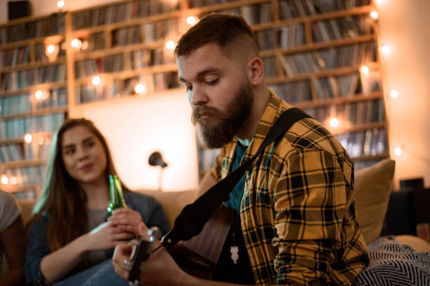 istock Man playing guitar on a house party while hanging with his friends 1325979166