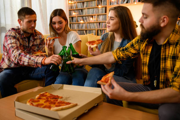 istock Friends eating pizza on a house party and having fun while drinking beer 1325979183