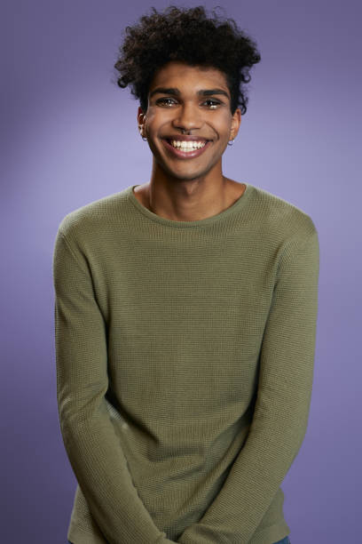 Portrait of transgender brunette model in olive t-shirt looks camera and smile Portrait of transgender brunette model in olive t-shirt looks camera and smile. Latino trans gender young man in casual pose on isolate purple background. Fashion people lifestyle androgyn stock pictures, royalty-free photos & images