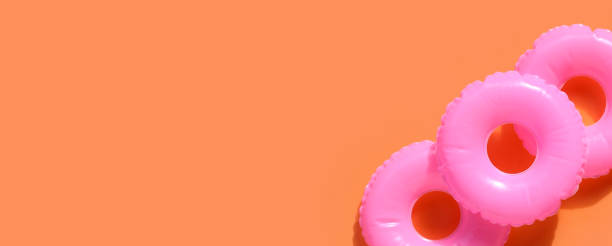 istock Inflatable rings on orange background. Summer background concept 1325985105