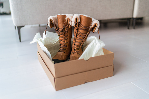 Nuevas botas de invierno comprando nuevos zapatos de senderismo de compras y entrega en línea. Abrir caja de zapatos en la sala de estar en casa photo