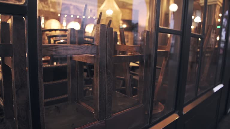 Cafe in London closed, forced to shut in Covid-19 Coronavirus pandemic lockdown in England, showing chairs and stools upside down on tables in restaurant and bar in hospitality industry