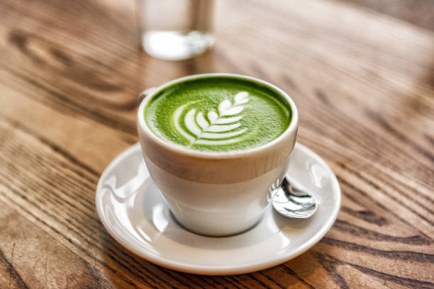 matcha latte green milk foam cup on wood table at cafe. trendy powered tea trend from japan - latté imagens e fotografias de stock