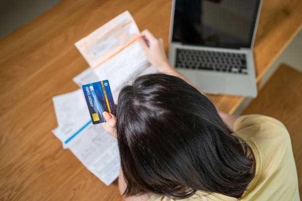 Top view of Depressed desperate Asian girl feel worry about financial problem in house. Stressed young woman look frustrated to paperwork and bill think of money debt, budget loss, bankruptcy at home. Top view of Depressed desperate Asian girl feel worry about financial problem in house. Stressed young woman look frustrated to paperwork and bill think of money debt, budget loss, bankruptcy at home. public utility stock pictures, royalty-free photos & images