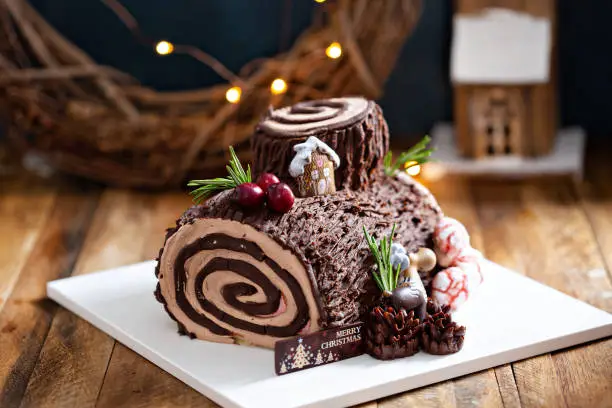 Yule log roll cake for Christmas decorated with chocolate ganache