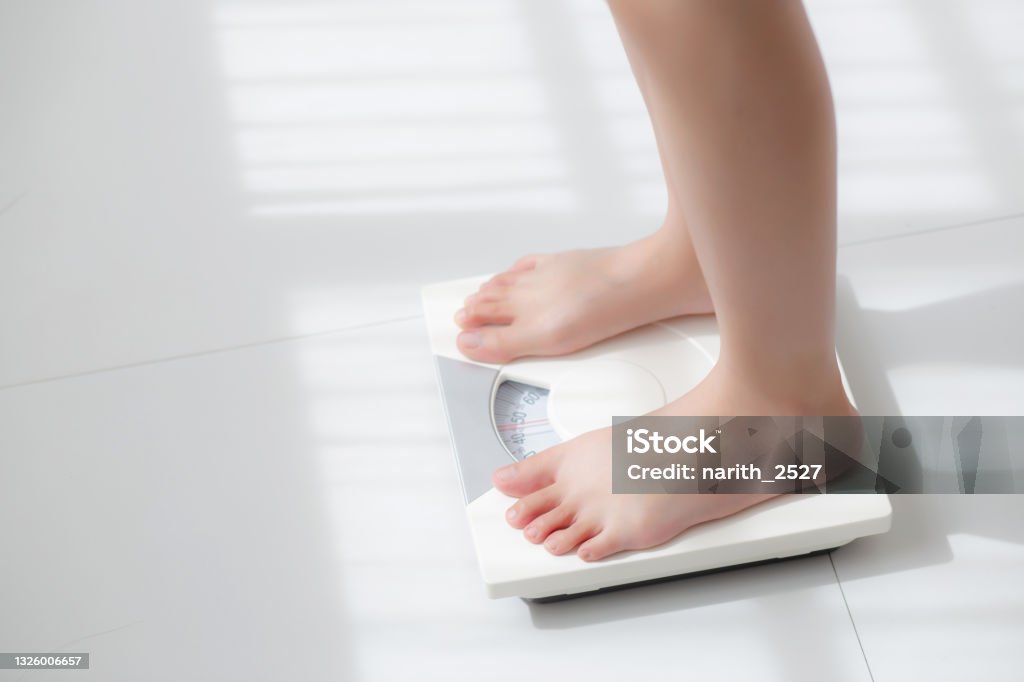 Lifestyle activity with leg of woman stand measuring weight scale for diet with barefoot, closeup foot of girl slim weight loss measure for food control and nutrition, healthy care and wellness concept. Weight Stock Photo